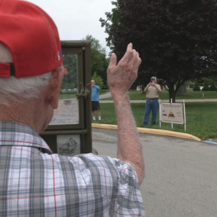 WWII veteran Damon Hawkins waves as he rides in a jeep around Seneca Park